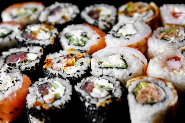 Sushi sobre un fondo negro. Sushi puesto en una mesa. Vista superior. Comida asiática o japonesa. Concepto de restaurante de sushi