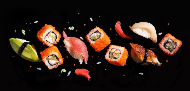 Sushi-Stücke zwischen Schnüppeln fliegen getrennt auf schwarzem Hintergrund.