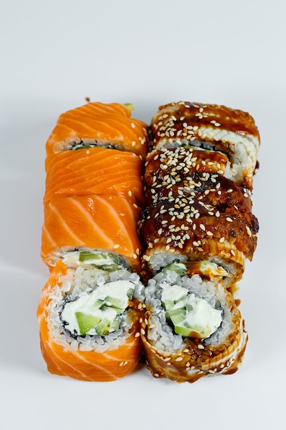 Sushi surtido. Rollo de sushi con aguacate, pepino. Rollo de sushi con salmón y caviar. Rollo de sushi con atún y caviar. Sobre un fondo claro. Comida japonesa. Vista desde arriba
