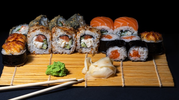 Sushi Um conjunto de rolos de sushi em uma travessa de bambu com wasabi, gengibre e pauzinhos