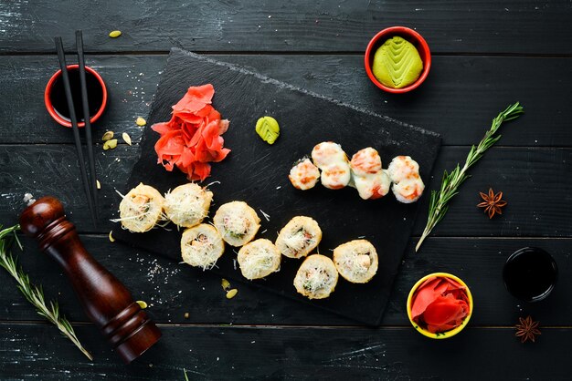 Sushi und Brötchen auf dem Teller Ansicht von oben Freier Platz für Ihren Text Auf schwarzem Hintergrund