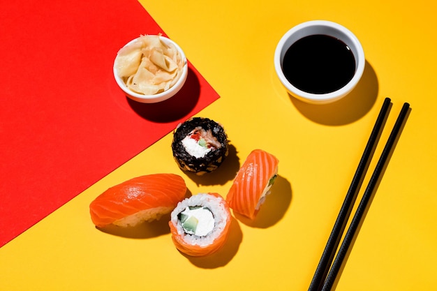 Sushi und Brötchen auf farbigem Hintergrund, Sojasauce, Ingwer. Mit hartem Licht