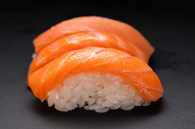 Sushi und Brötchen. Brötchen für das asiatische Menü. Auf einem schwarzen Tisch. Roher Fisch und Reis. Garnelen, Lachs