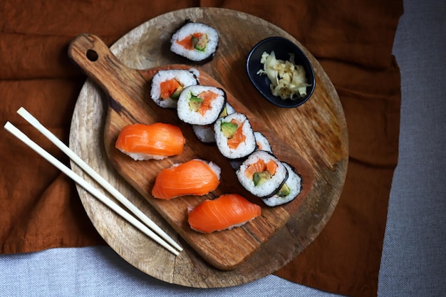 Sushi und Brötchen mit Avocado und Lachs auf einem Holzbrett