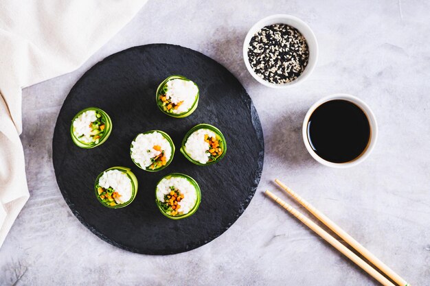 Foto sushi vegetal feito de pepino de arroz e cenouras em uma tábua de ardósia na mesa