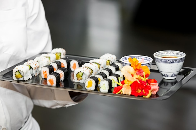 Sushi-Vorspeisen auf einem Tablett, das von einem Kellner gehalten wird