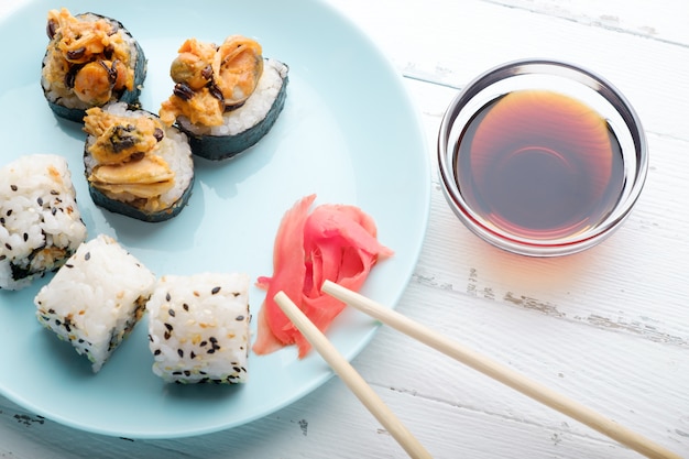 Sushirollen in der blauen Platte, in den Essstäbchen und in der Sojasoße