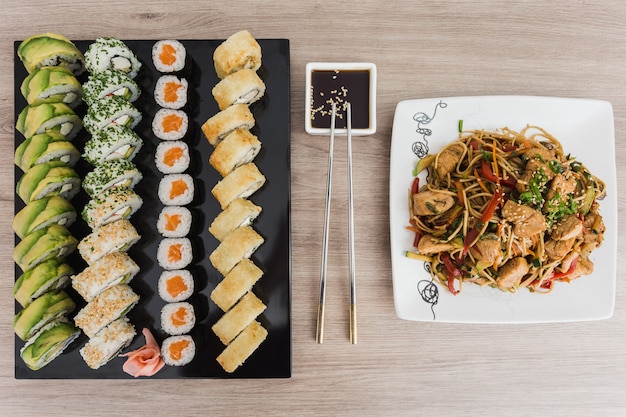 Sushirollen mit yakisoba und Sojasoße auf einem Holztisch