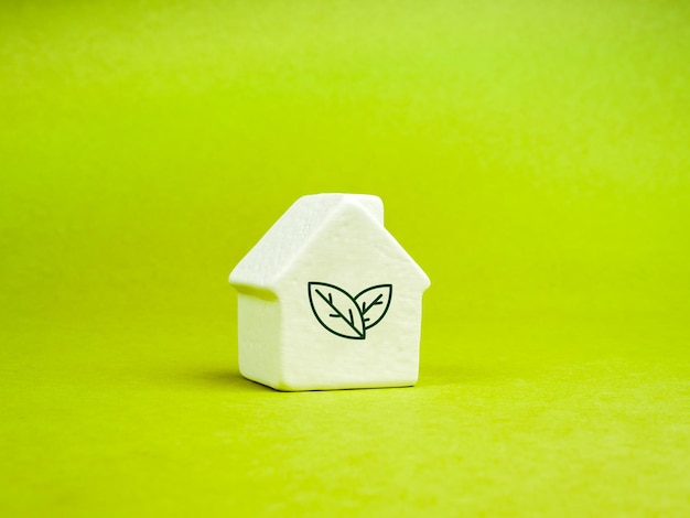 Foto sustentabilidade em casa cuidado com a terra responsabilidade ambiental eco-conceitos familiares símbolo de folha ecológica verde em modelo moderno pequeno casa branca em fundo de papel reciclado verde claro estilo minimalista