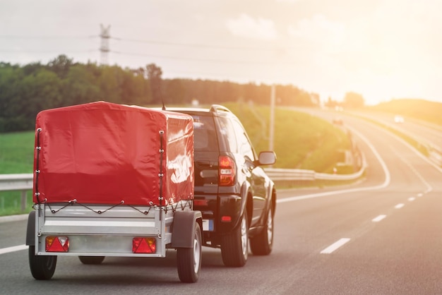 SUV com trailer vai para a rodovia Movendo coisas com um pequeno trailer alugável