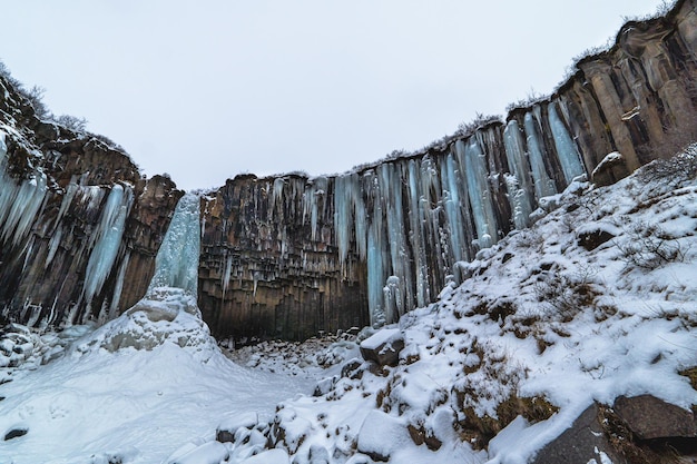 Svartifoss islândia cachoeira negra completamente congelada com estalactites azuladas e neve