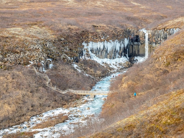 Svartifoss-Wasserfall Island im Nationalpark Vatnajokull im schwarzen Larvensand-Ebenenwasser gefrieren