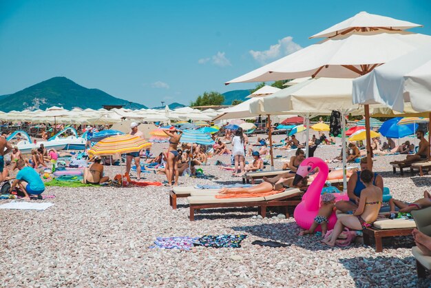 SVETI STEFAN MONTENEGRO 18 de julio de 2018 hora de verano gente en la playa rocosa sombrillas y sillas de sol