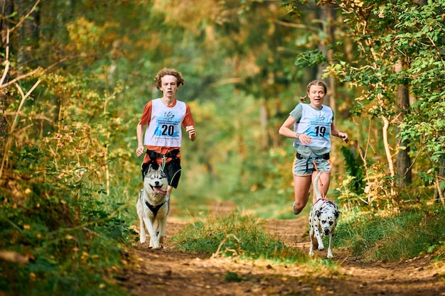 Svetly, Óblast de Kaliningrado, Rusia - 2 de octubre de 2021 - Canicross dog mushing race, Siberian Husky y Dalmatian dog running adjunto a mushers masculinos y femeninos, carreras de perros de trineo