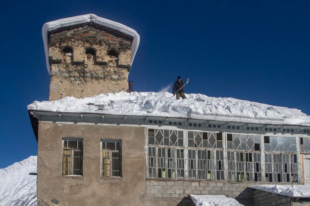 Swanetien Georgien 1. Februar 2020 Ein Mann wirft Schnee vom Dach neben dem Svan-Turm