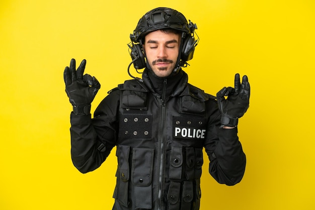 SWAT hombre caucásico aislado sobre fondo amarillo en pose zen