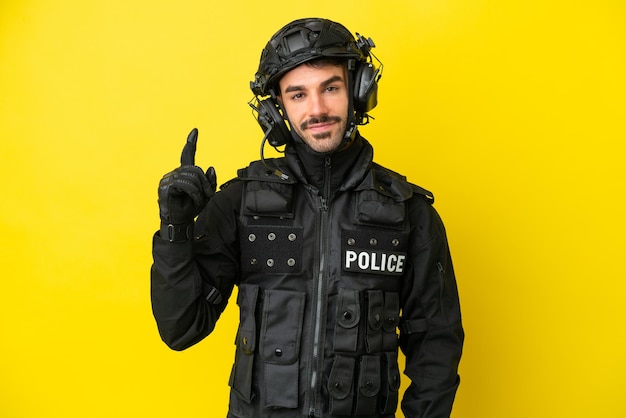 SWAT homem caucasiano isolado em fundo amarelo mostrando e levantando um dedo em sinal do melhor