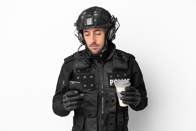 SWAT homem caucasiano isolado no fundo branco segurando café para levar e um celular