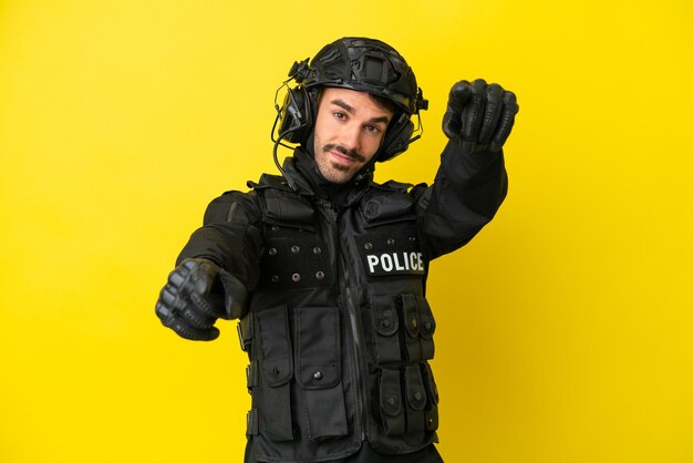 SWAT kaukasischer Mann isoliert auf gelbem Hintergrund zeigt mit dem Finger auf dich, während er lächelt