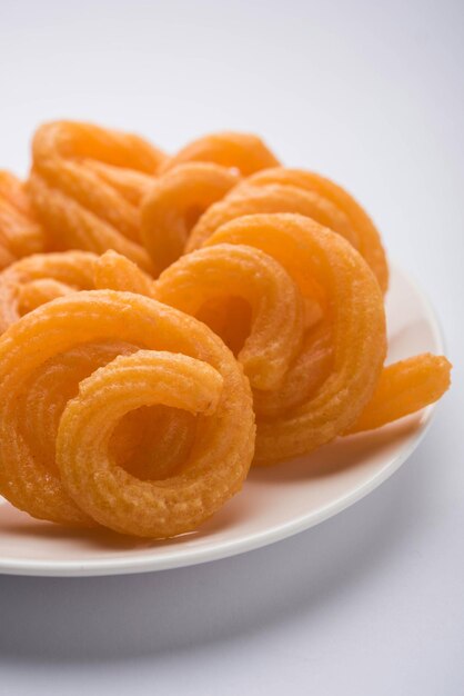 Sweet Paneer Jalebi serviert in einer Keramikplatte über buntem oder hölzernem Hintergrund. Selektiver Fokus