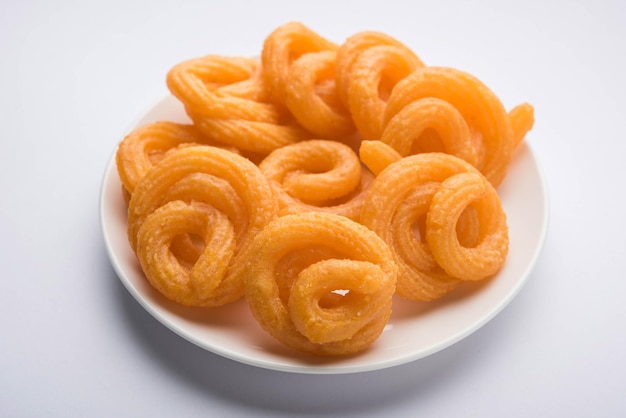 Sweet Paneer Jalebi serviert in einer Keramikplatte über buntem oder hölzernem Hintergrund. Selektiver Fokus