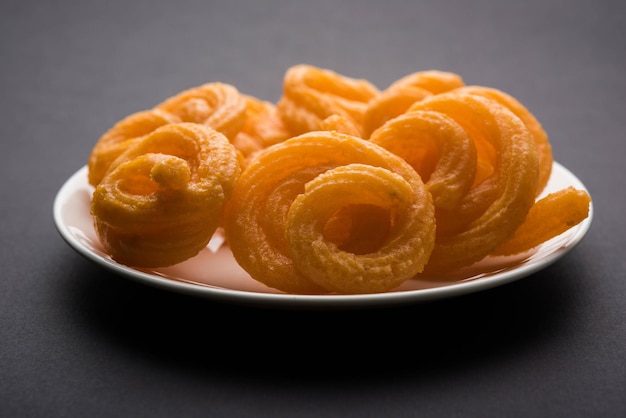 Sweet Paneer Jalebi serviert in einer Keramikplatte über buntem oder hölzernem Hintergrund. Selektiver Fokus