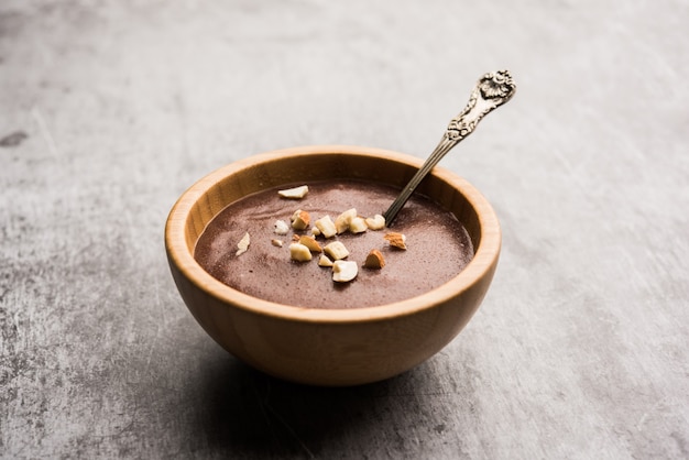 Sweet Ragi Malt ou Healthy Ragi Porridge em uma tigela guarnecida com frutas secas esmagadas