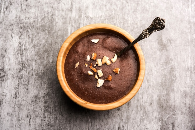 Foto sweet ragi malt ou healthy ragi porridge em uma tigela guarnecida com frutas secas esmagadas