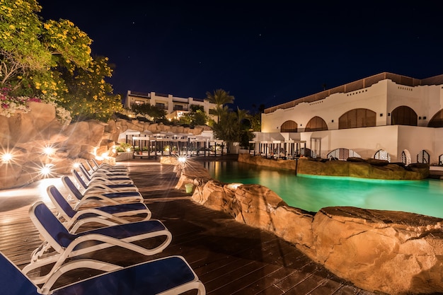 Swimmingpool bei Nachtbeleuchtung und Luxusgebäude dahinter