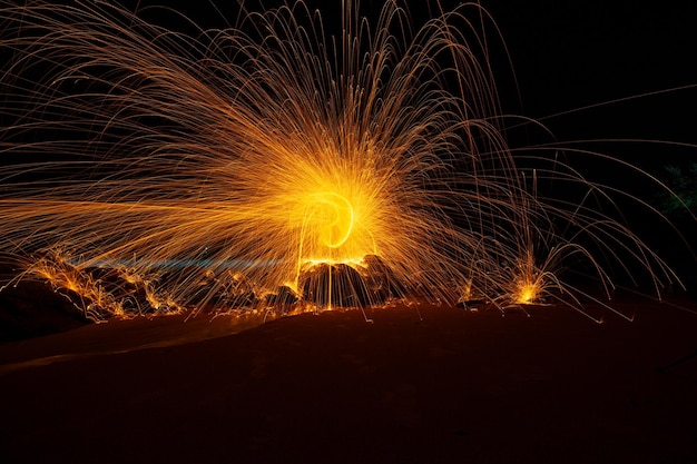 Swing fire Swirl Stahlwolle Lichtfotografie über den Stein mit Reflex im Wasser Schönes Licht in der Sonnenaufgangs- oder Sonnenuntergangszeit lange Belichtungsgeschwindigkeitsbewegungsart