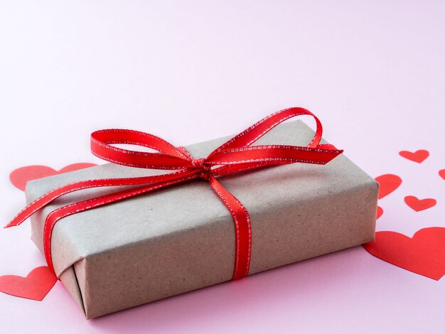 Symbol des Valentinstags - Geschenkbox auf einem rosa Hintergrund mit vielen roten Herzen, Seitenansicht