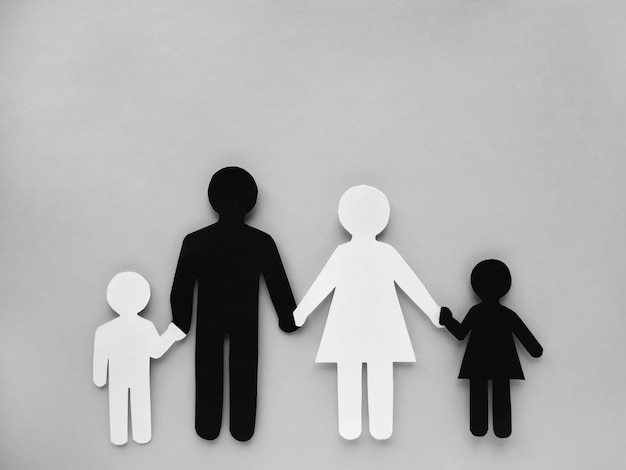 Symbol einer Person und Familie aus Schwarzweiss-Papier ausgeschnitten. Interracial Familie.