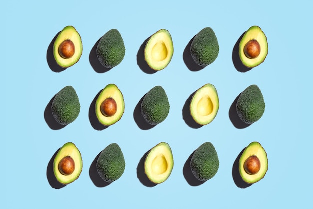 Symmetrische Zusammensetzung von Avocados-Scheiben auf blauem Hintergrund. Draufsicht.