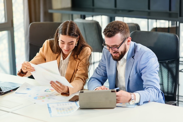 Sympathische, zielgerichtete Geschäftspartner studieren Finanzdokumente sorgfältig mit Diagrammen am Besprechungstisch im Besprechungsraum.