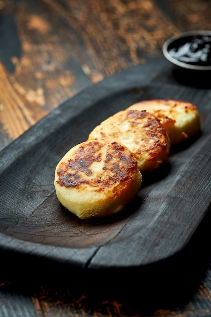 Syrnyky ucraniano en una tabla de madera sobre un fondo de madera tortitas de queso frito de estilo rústico