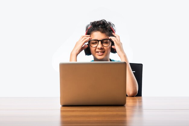 Syudent masculino indio o niño que estudia en línea usando la computadora portátil. Niño asiático que asiste a la escuela en línea usando computadora