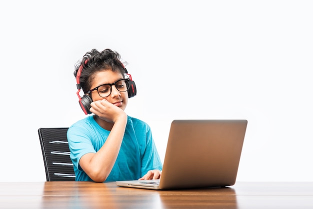 Syudent masculino indio o niño que estudia en línea usando la computadora portátil. Niño asiático que asiste a la escuela en línea usando computadora