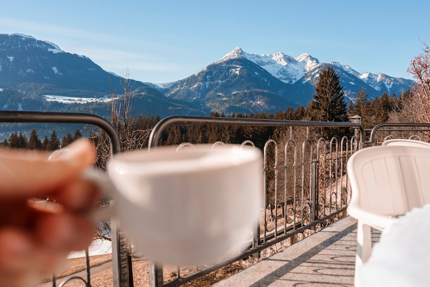 Szenische Ansicht des schneebedeckten Berges mit der Person, die Kaffeetasse hält