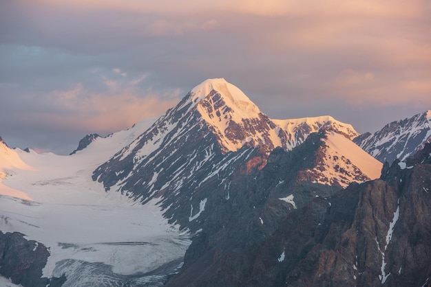 Szenische Luftaufnahme zu hohen Schneebergen am frühen Morgen in der Morgendämmerung Ehrfürchtige Landschaft mit sonnendurchflutetem goldenem Gipfel in bewölktem Himmel bei Sonnenaufgang Morgenlandschaft mit schneebedecktem Gipfel im goldenen Sonnenlicht