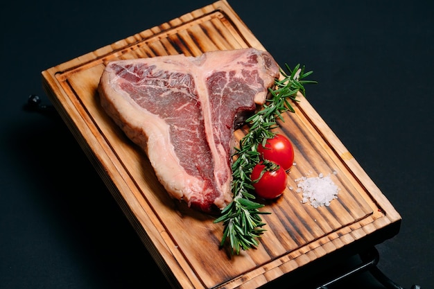 Foto t-bone de bistec de carne cruda sobre un fondo negro.