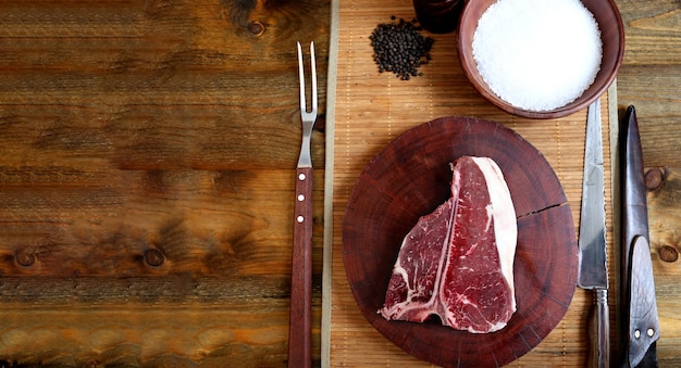 T-Bone Rohes Fleisch mit Knochen zum Grillen auf Holzhintergrund vorbereiten