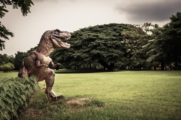 Foto t-rex com galhos de árvores contra a natureza