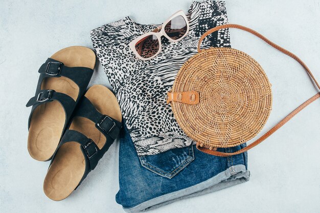 T-Shirt mit Animal-Print, blaue Jeansshorts, modische Rattantasche, Sonnenbrille.