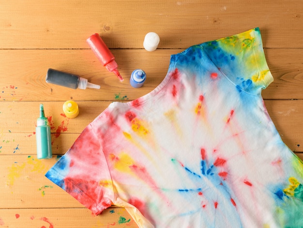 T-shirt pintada no estilo tie dye em uma mesa de madeira marrom.