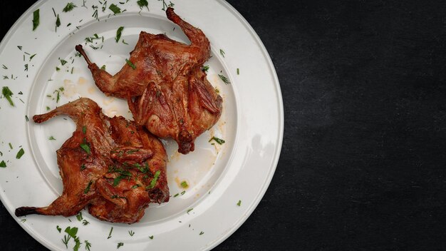 Tabaco de frango frito com ervas em um prato branco sobre fundo escuro