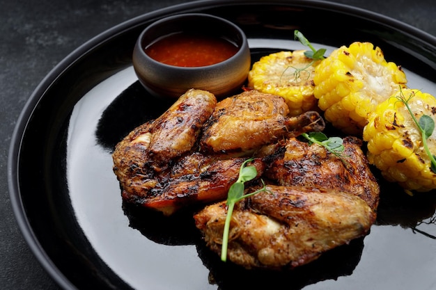 Tabaco de frango grelhado com molho e milho em um fundo escuro