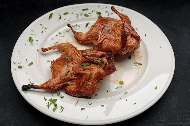 Tabaco de pollo frito con hierbas en un plato blanco sobre un fondo oscuro