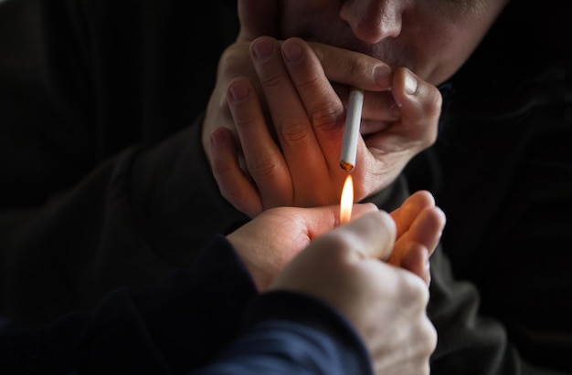 tabagismo, abuso de substâncias, vício e conceito de maus hábitos - close-up de jovens acendendo cigarro ao ar livre