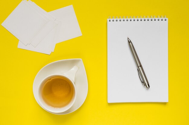 Tabela amarela denominada da mesa de escritório da fotografia com caderno, o computador, fontes e o copo vazios do T.