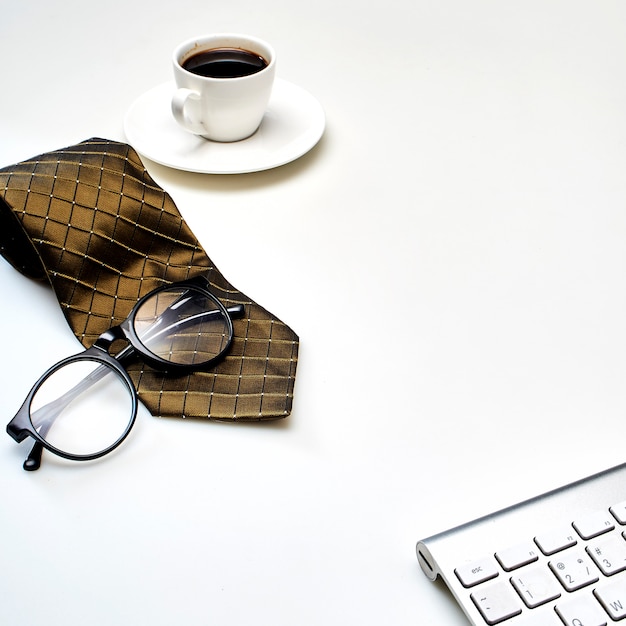 Foto tabela branca moderna do desktop do escritório com uma xícara de café, gravata e outras fontes.